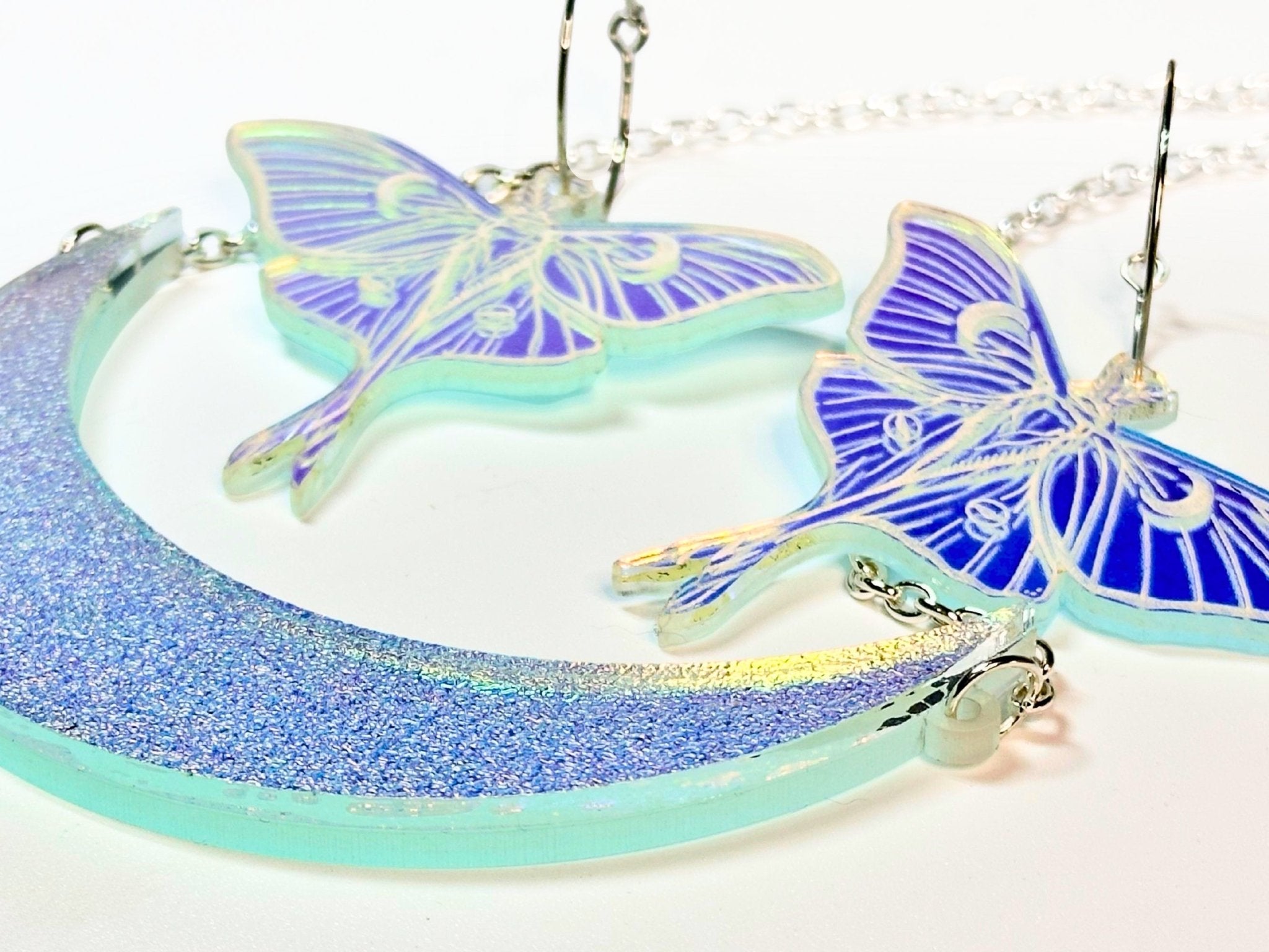 Close-up of textured iridescent crescent moon necklace and luna moth earrings