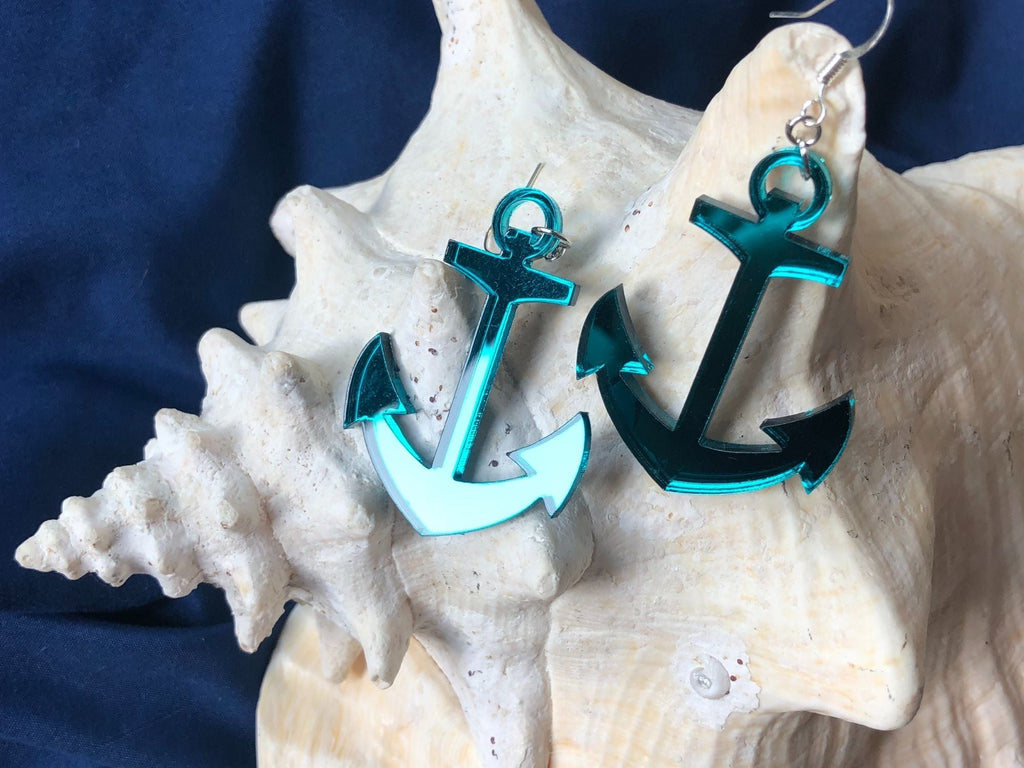 Teal anchor earrings displayed on seashells