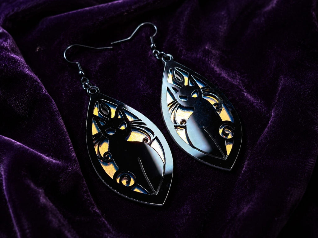 Layered black and frosted iridescent acrylic cat earrings reflecting rainbow colors