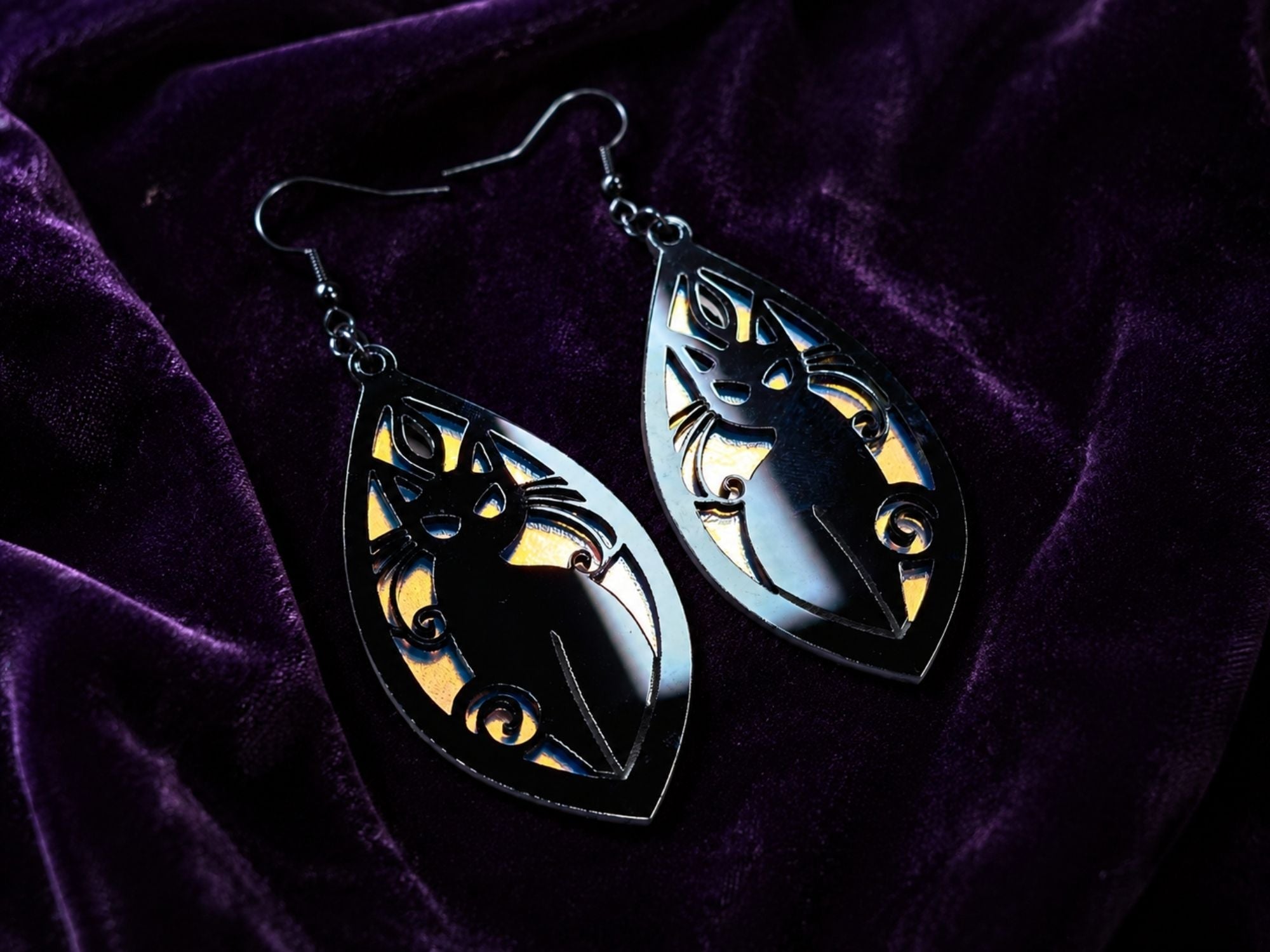 Layered black and frosted iridescent acrylic cat earrings reflecting rainbow colors