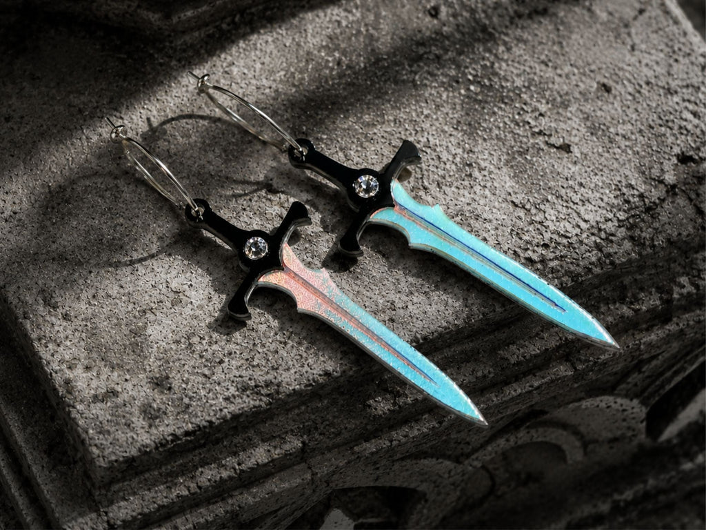 Fantasy-inspired sword earrings photographed on dark stone surface