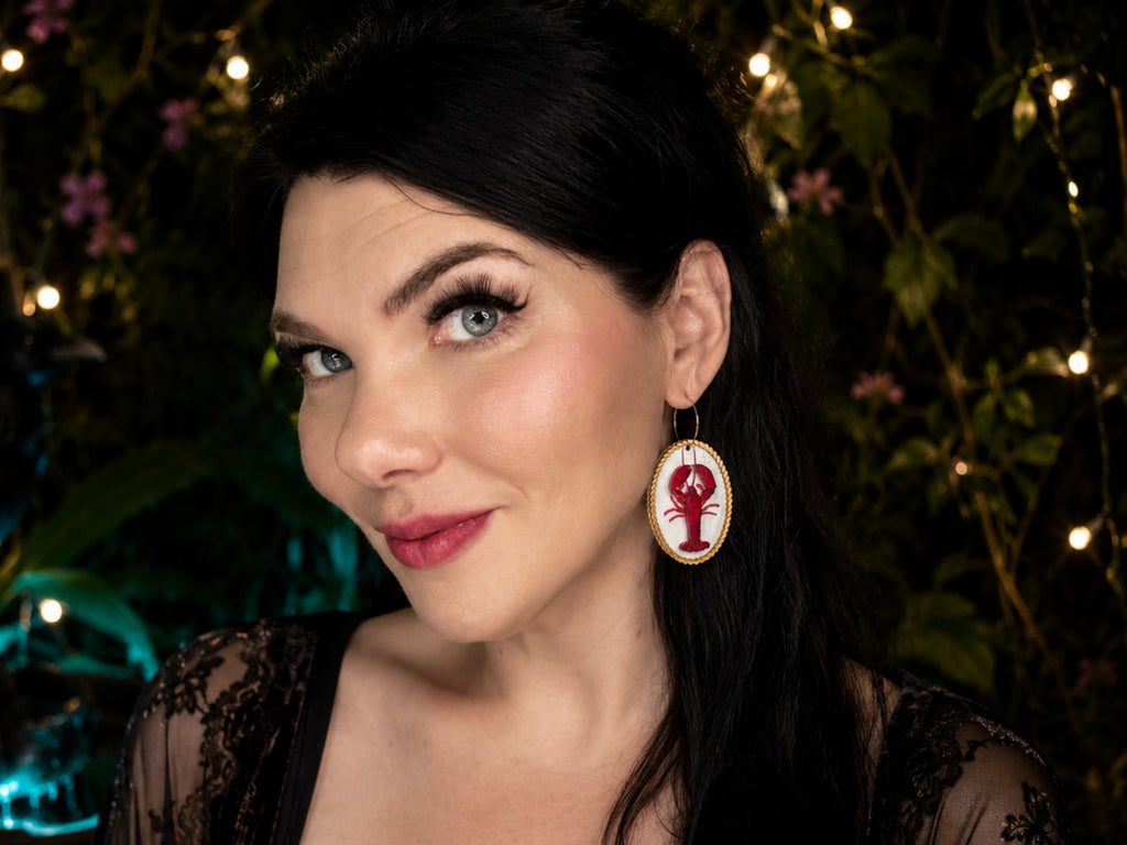 Model wearing red lobster statement earrings with original Painted Raina artwork