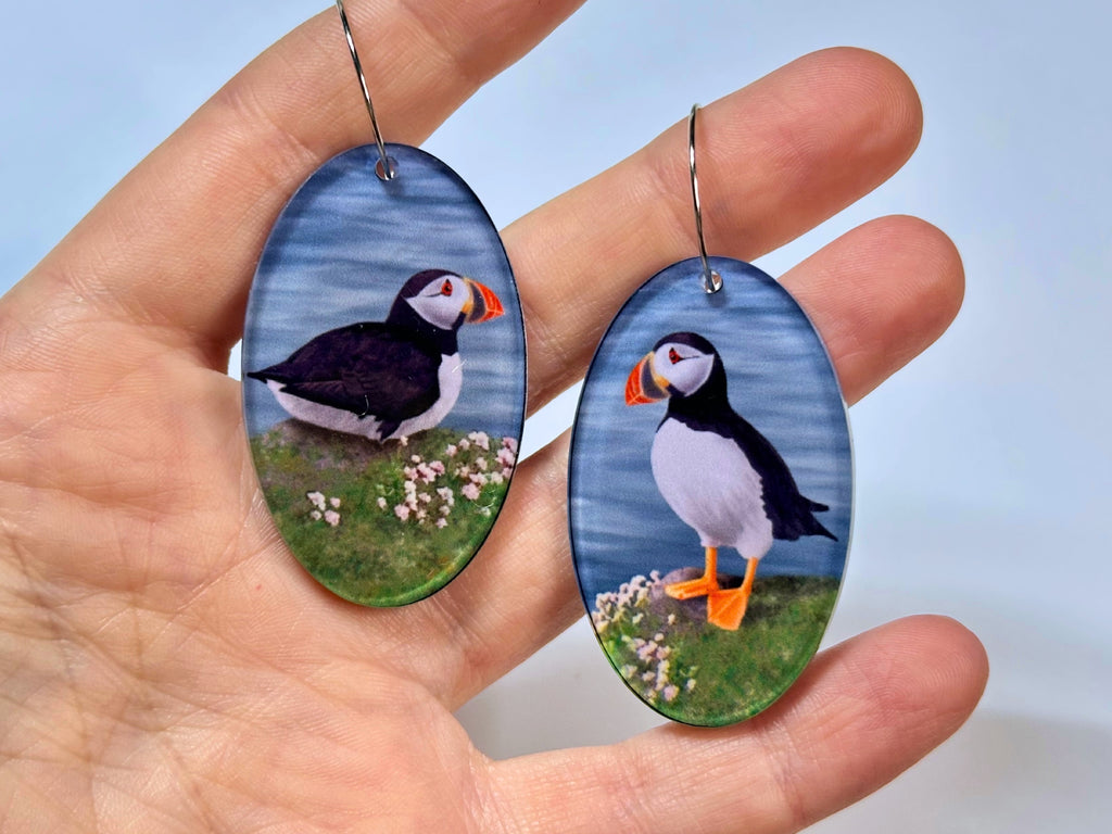 Hand holding lightweight puffin statement earrings showing their size