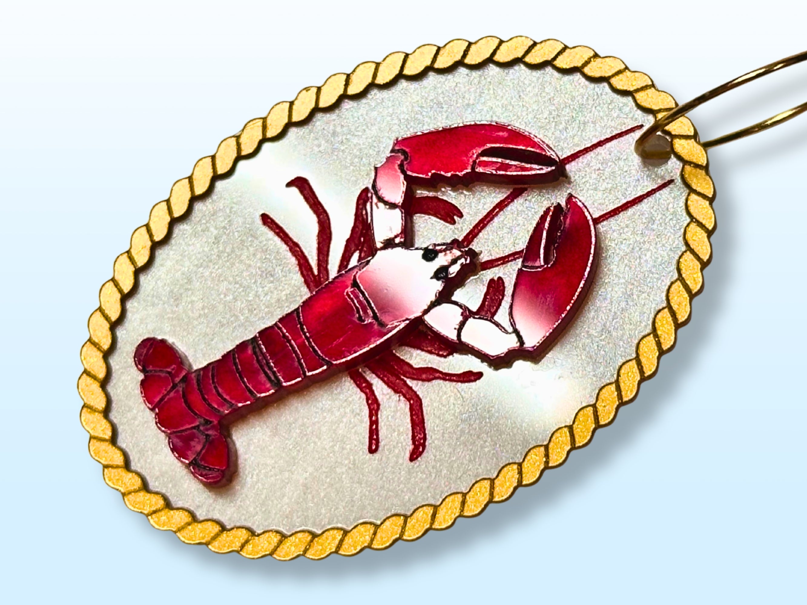 Close view of red lobster earring showing engraved and layered details