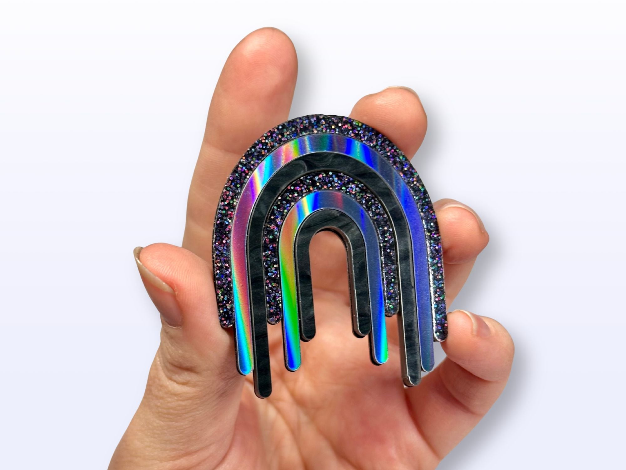 Hand holding Full Spectrum Rebel Drip Brooch for scale
