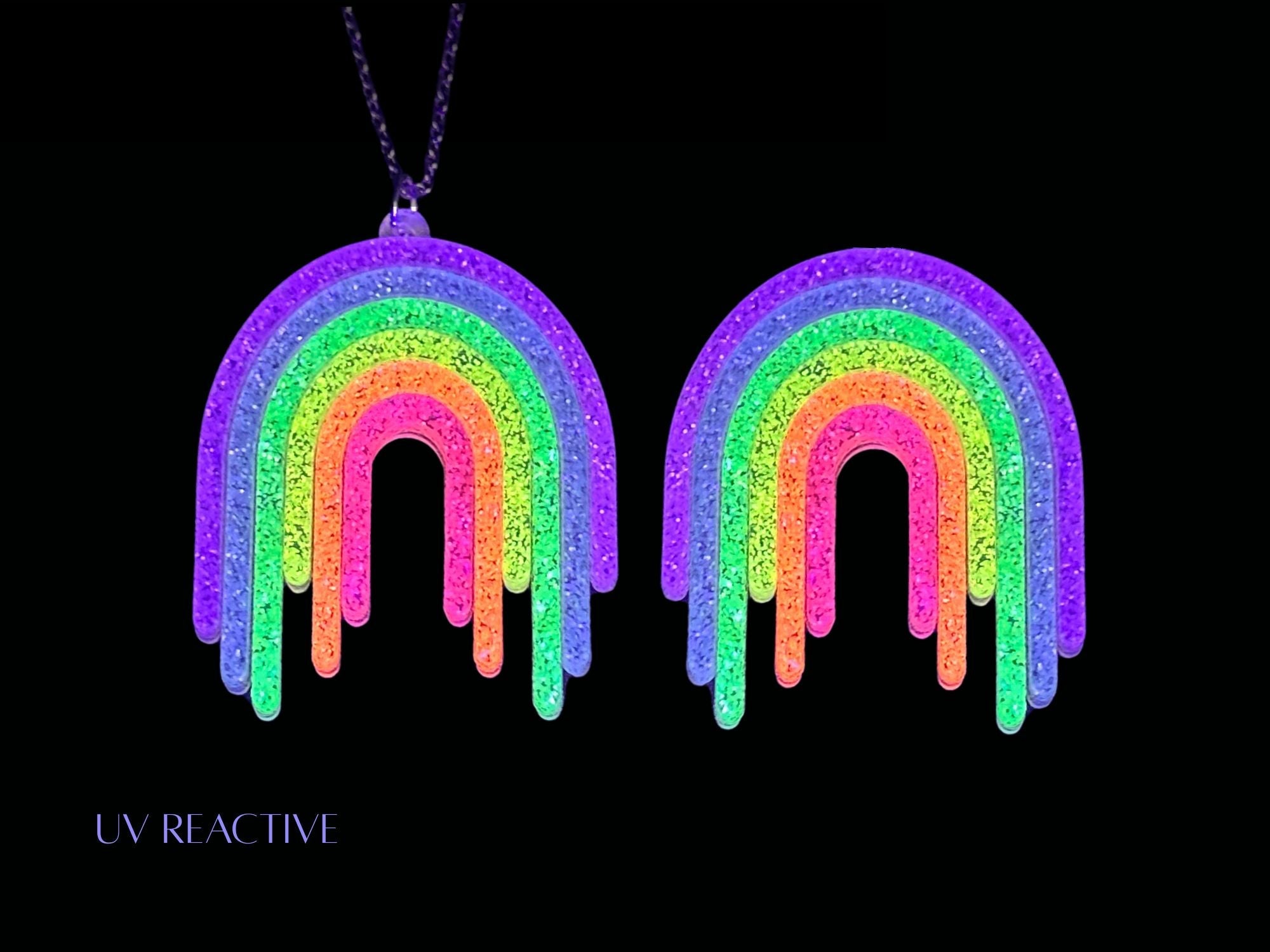 UV reactive Full Spectrum Rebel Rainbow Rave matching pendant and brooch editorial image on black background.