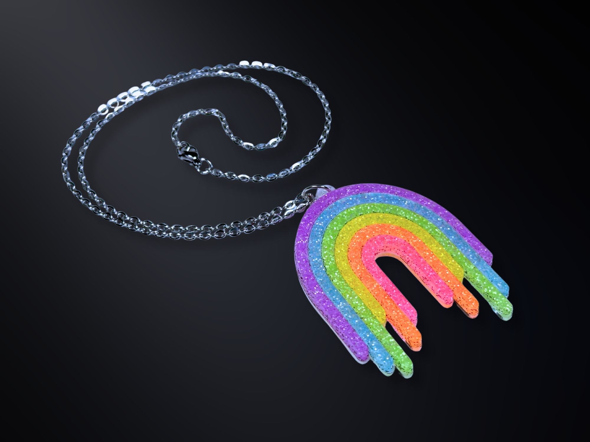 Full Spectrum Rebel Rainbow Rave drip pendant necklace in layered glitter acrylic on dark gradient background.