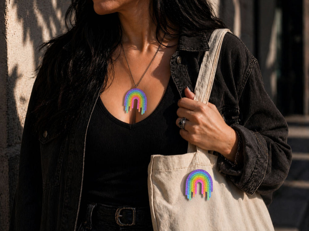 Model wearing Full Spectrum Rebel Rainbow Rave drip pendant and matching rainbow brooch with black outfit.
