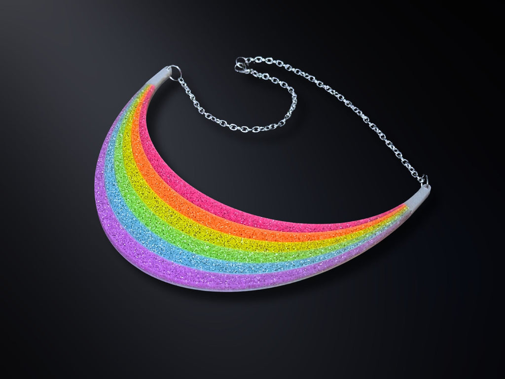 Full Spectrum Rebel Rainbow Rave arc statement necklace in layered glitter acrylic on dark gradient background.