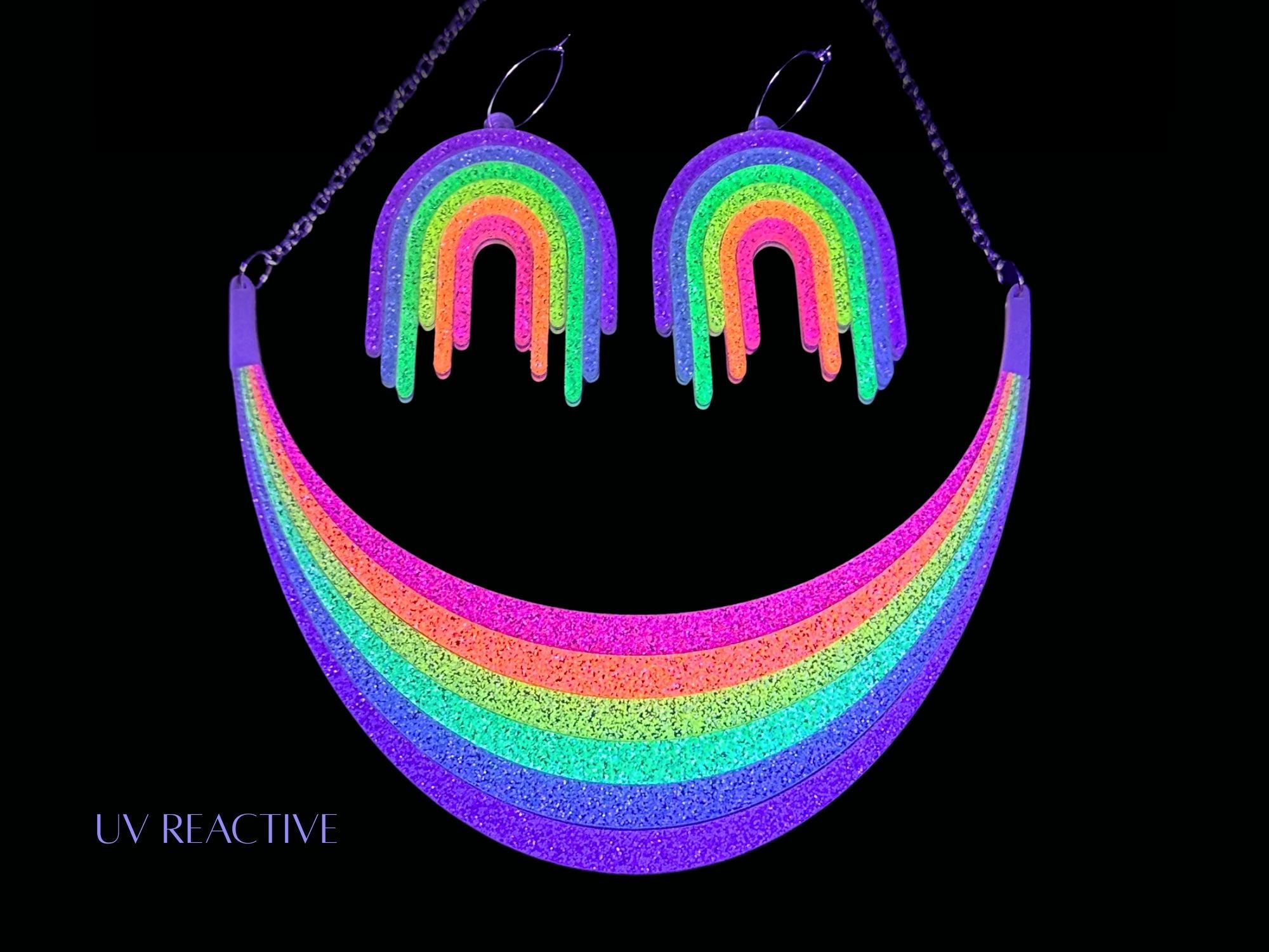 UV reactive Full Spectrum Rebel Rainbow Rave matching necklace, pendant, and earrings editorial image on black background.