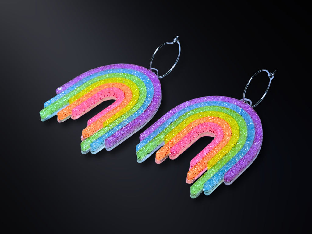 Full Spectrum Rebel Rainbow Rave drip earrings in layered glitter acrylic on dark gradient background.