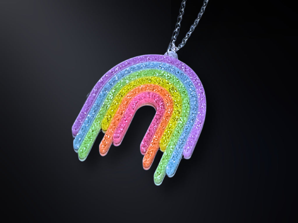 Full Spectrum Rebel Rainbow Rave drip pendant necklace in glitter acrylic on dark gradient background.