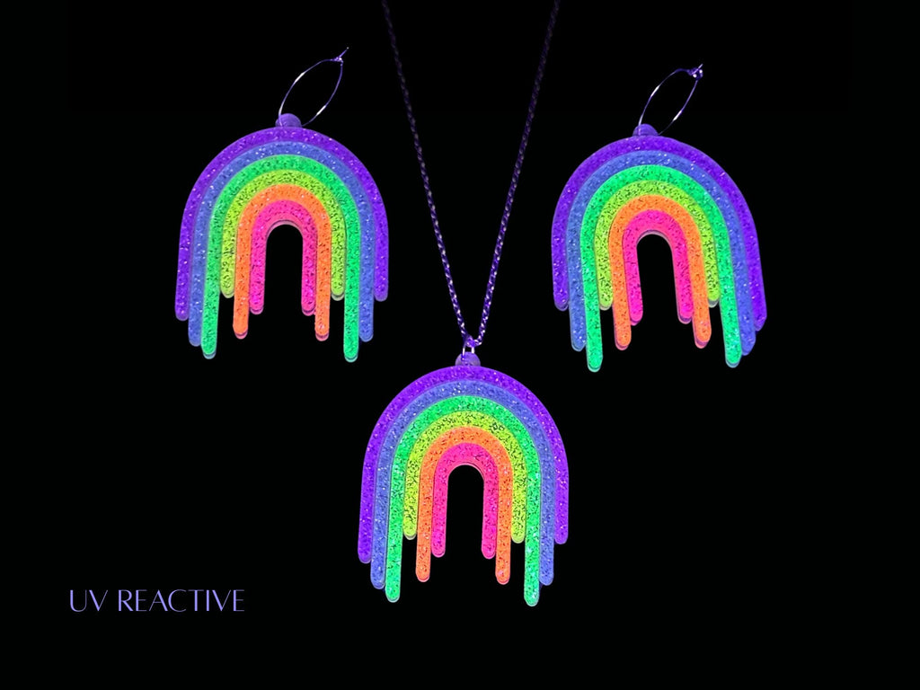 UV reactive Full Spectrum Rebel Rainbow Rave matching pendant and earrings editorial image on black background.